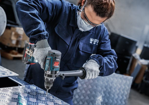 佩戴安全设备的人员正在钻入金属板。