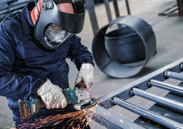 佩戴安全设备的人研磨金属，产生火花。