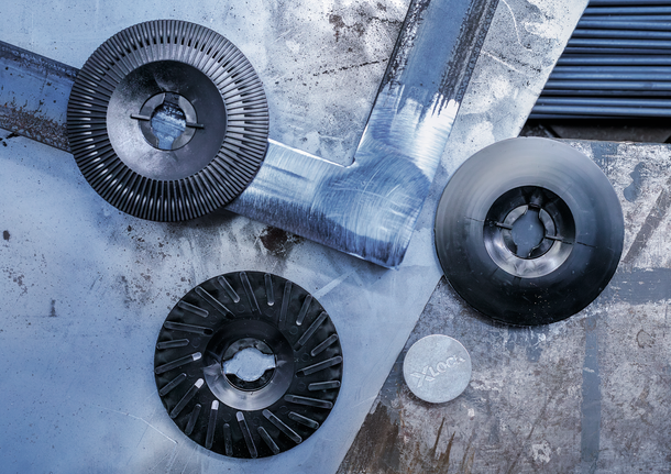 三个不同的研磨盘和一个金属适配器放在有划痕的金属表面上。