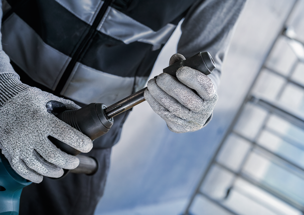 佩戴安全设备的人员将金属钻头安装到电动工具上。