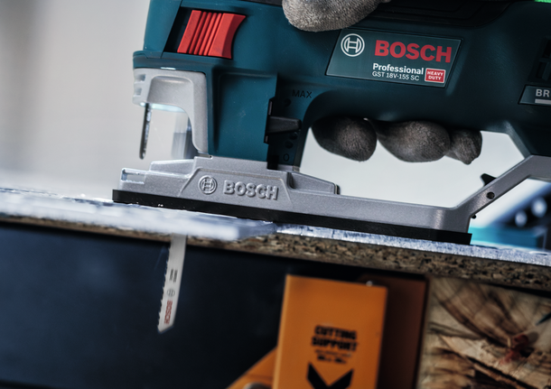 一名佩戴安全设备的人使用曲线锯切割木板。