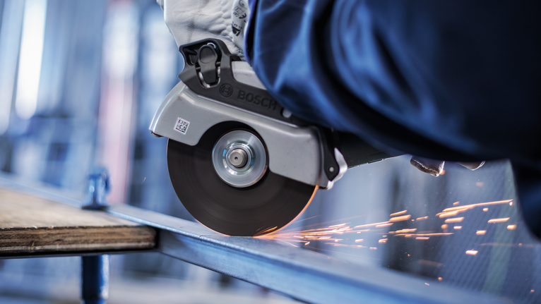 工人佩戴安全设备，使用角磨机切割金属，产生火花。.