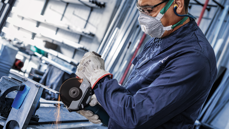 佩戴安全设备的人研磨金属，产生火花。