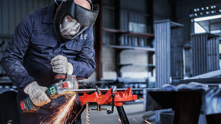 佩戴安全设备的人使用电动工具研磨金属，产生火花。