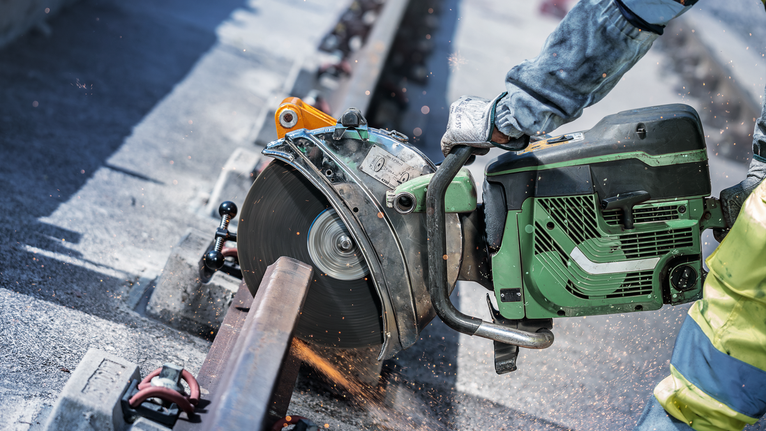 一名佩戴安全设备的人用电锯切割金属栏杆。