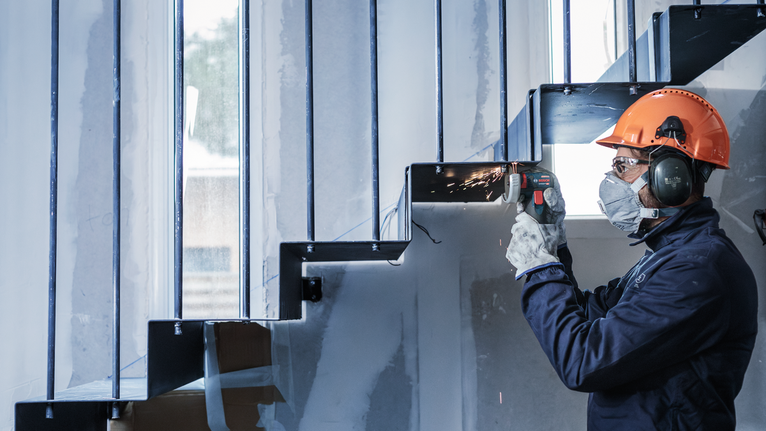 一名佩戴安全设备的人磨擦金属楼梯，产生火花。