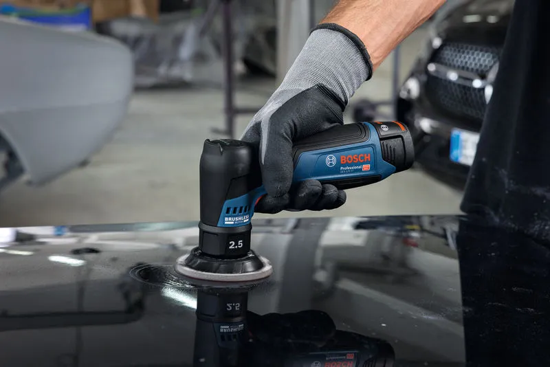 一名佩戴安全设备的人员使用随机轨道砂光机抛光汽车表面。.