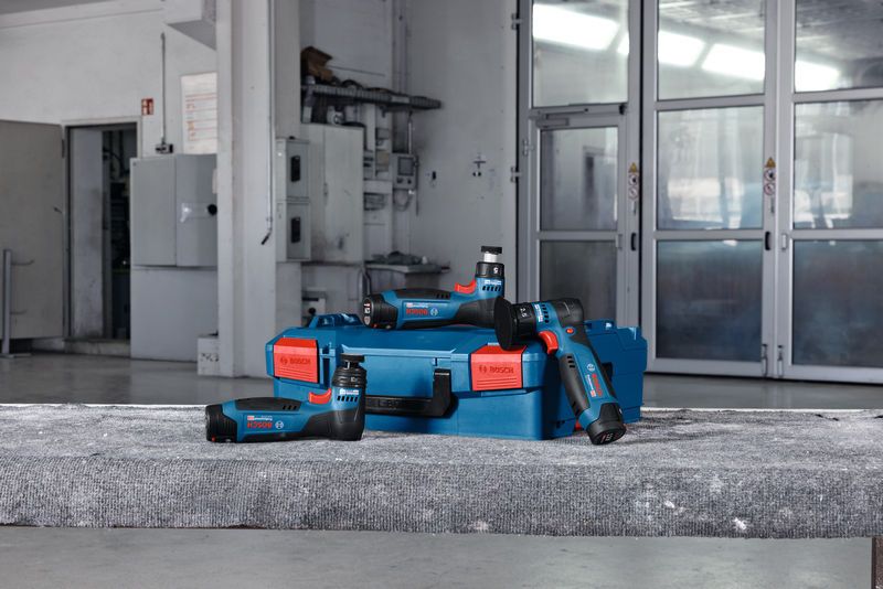 无绳随机轨道砂光机和蓝色盒子放置在车间的混凝土表面上。.