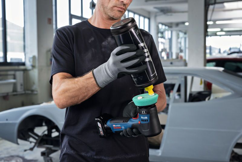 一名佩戴安全设备的人员在汽车修理厂内为抛光机上抛光。.