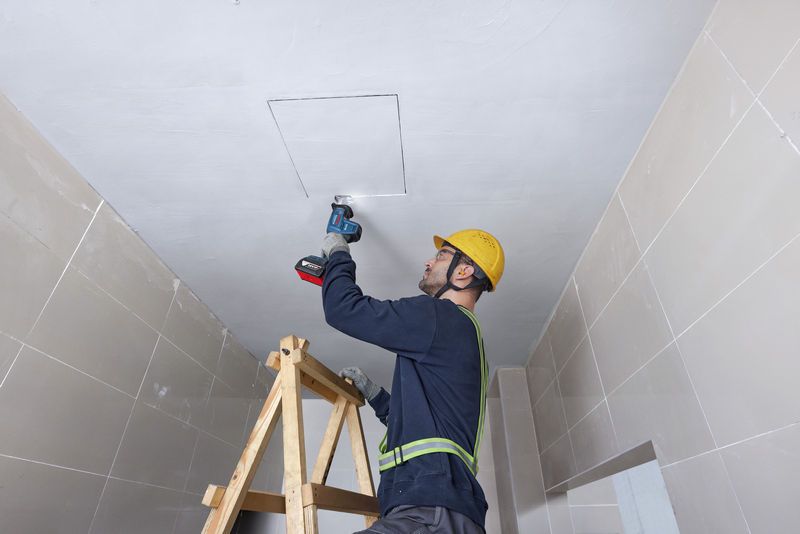 一名佩戴安全设备的人员使用往复锯切割天花板。.