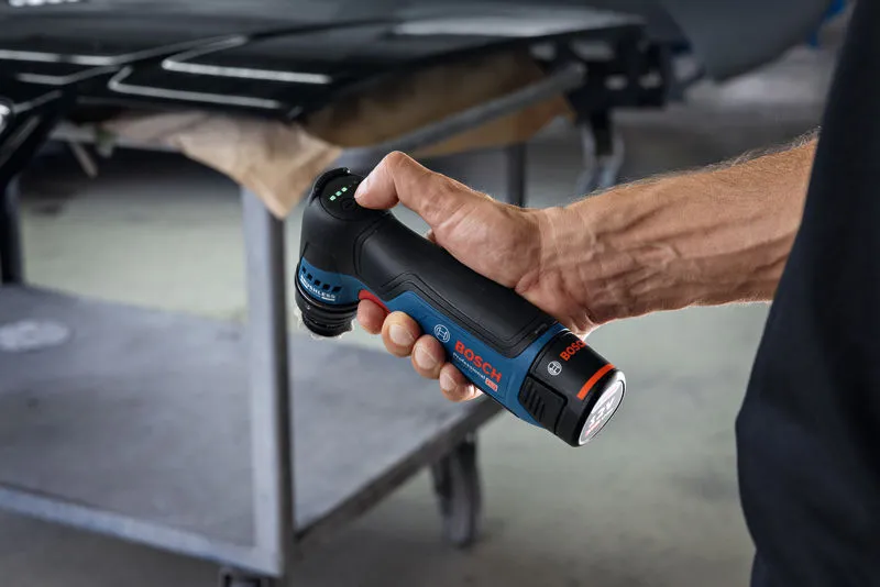 一个人在金属工作台附近拿着一台无绳轨道砂光机。.