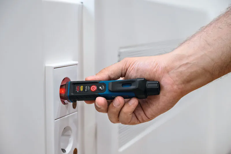 一个人在电源插座附近使用非接触式电压测试仪。.