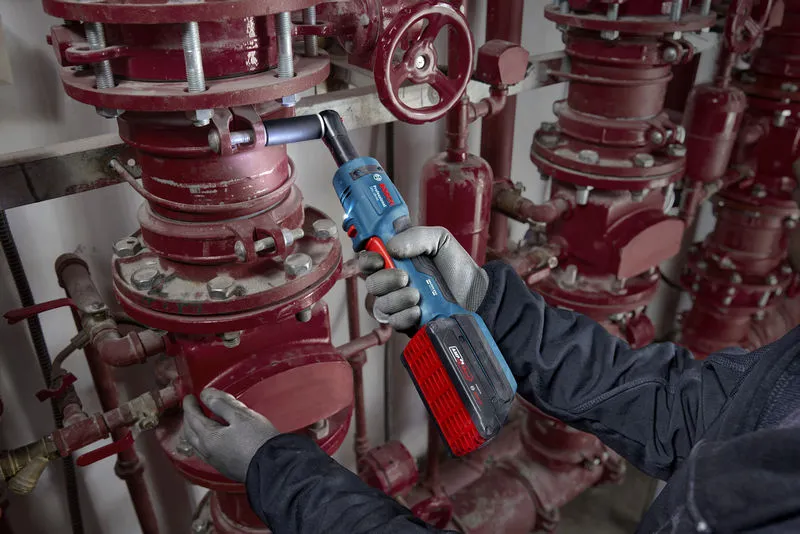 一名佩戴安全设备的人员正在使用无绳棘轮扳手拧紧管道螺栓。.