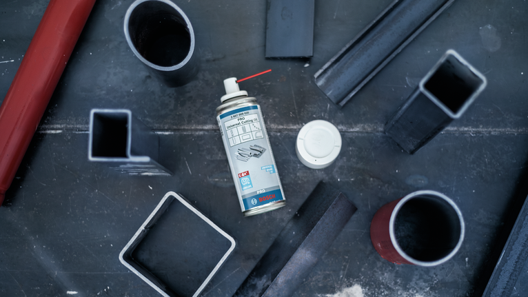 喷雾罐放置在金属工作台上，周围环绕着各种钢管。