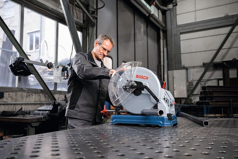 一名佩戴安全设备的人员在车间操作金属切割锯。.