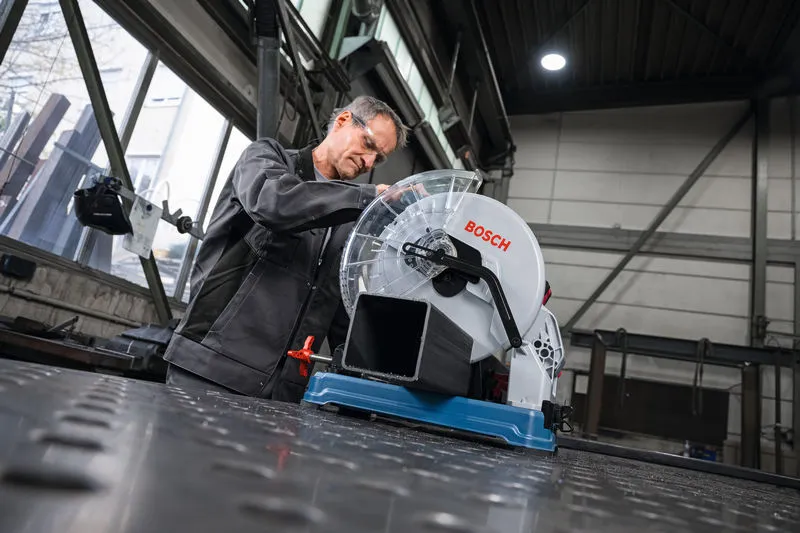 一名佩戴安全设备的人员准备用金属切割锯切割金属管。.