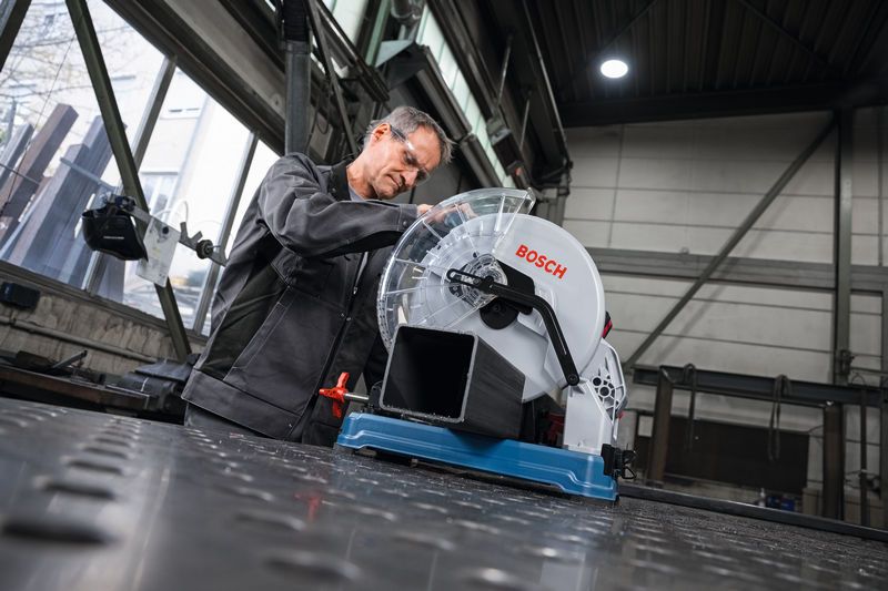 一名佩戴安全设备的人员准备用金属切割锯切割金属管。.