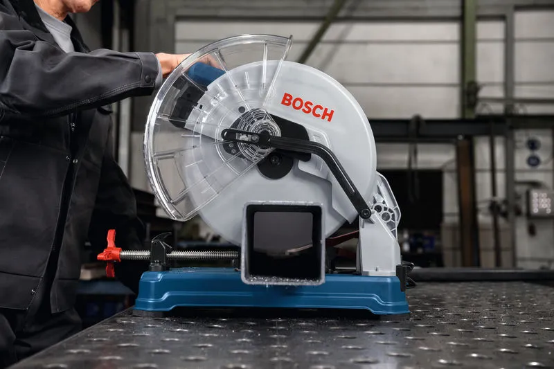 一名佩戴安全设备的人员操作金属切割锯切割钢管。.