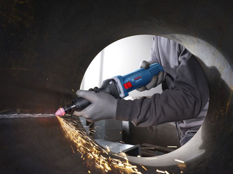 一名佩戴安全设备的人员使用直磨机打磨金属管道内部。.