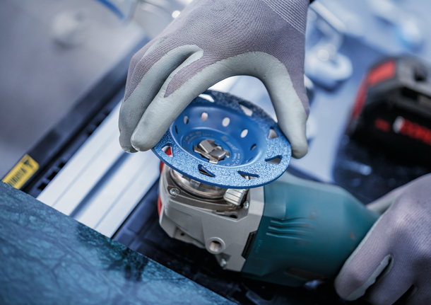 佩戴安全设备的人员将砂轮安装到电动工具上。.