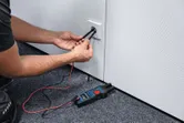 人们使用叉形电流表测量电源插座的电压。.