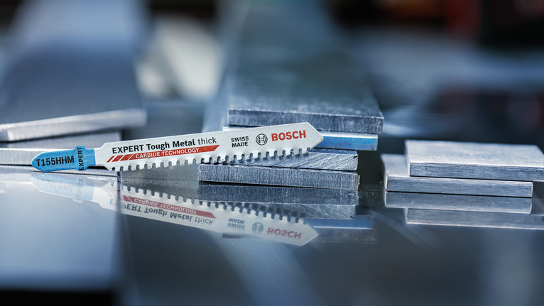 拼图锯刀片放置在反射表面上的堆叠金属板上。