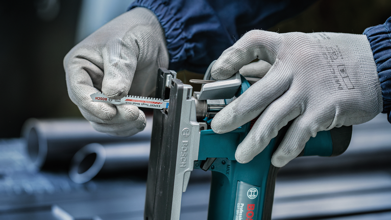 佩戴安全设备的人员将锯片插入电动工具。