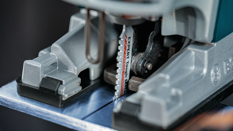 拼图锯刀片切割金属板的特写。