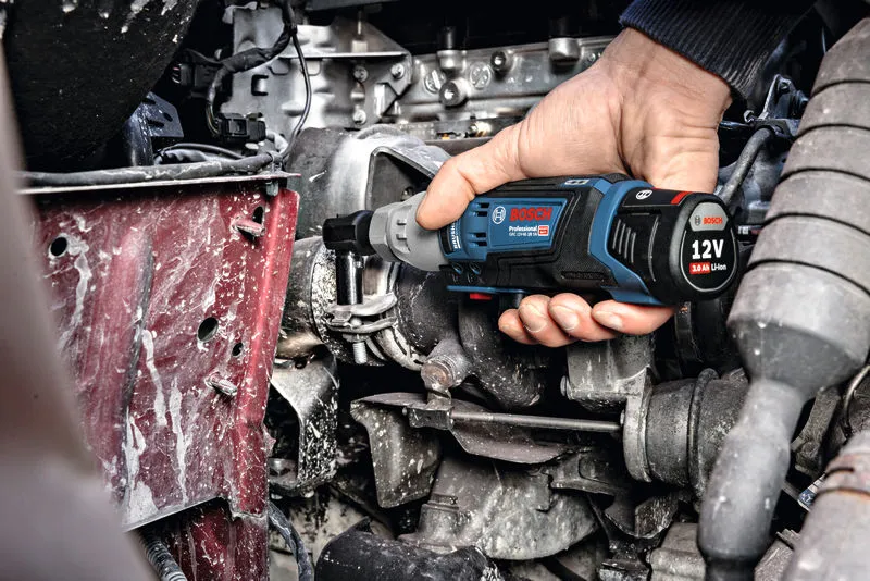 一个人使用无绳棘轮扳手紧固发动机舱内的螺栓。.