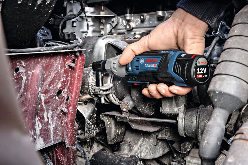 一个人使用无绳棘轮扳手紧固发动机舱内的螺栓。.