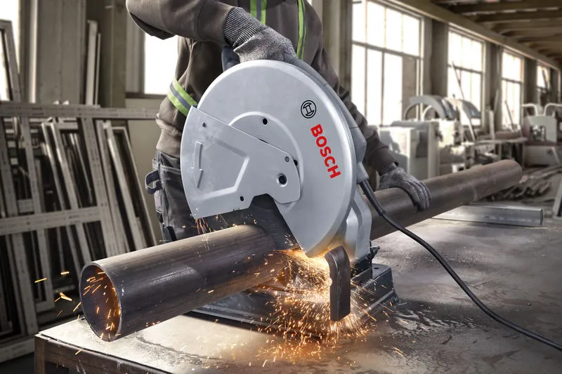 一名佩戴安全设备的人员正在用切割锯切割金属管。.