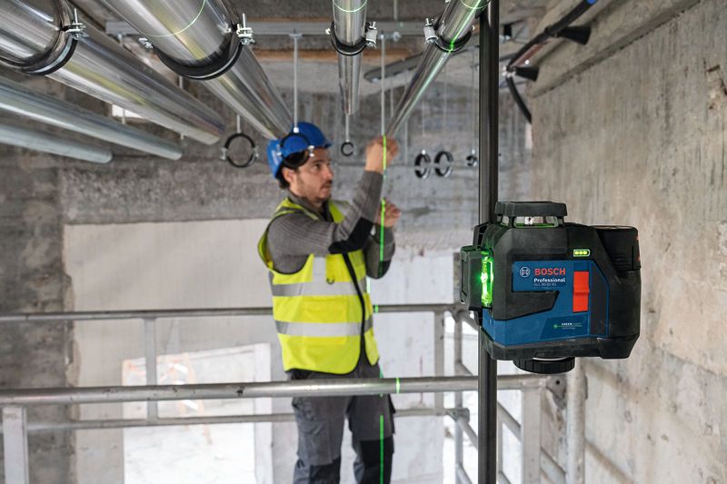 一名佩戴安全设备的人员使用激光调平工具对准管道。.