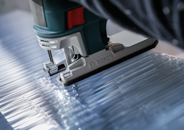 沿直线用拼图锯切割透明丙烯酸板。.