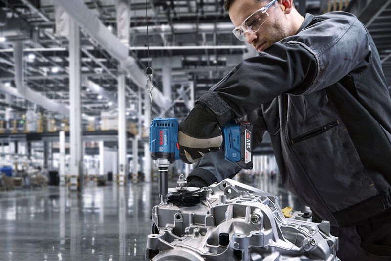 一名佩戴安全设备的人员使用无绳电钻对发动机部件进行维修。.