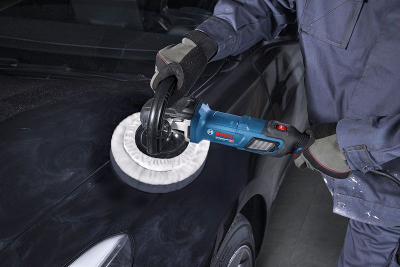 一名佩戴安全设备的人正在使用抛光机抛光黑色汽车引擎盖。.