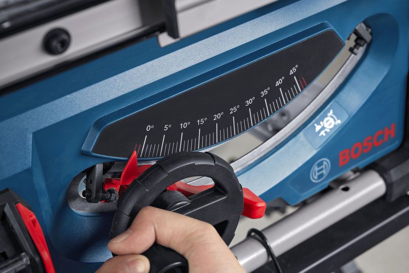 一个人正在调整蓝色台锯上的角度计。.