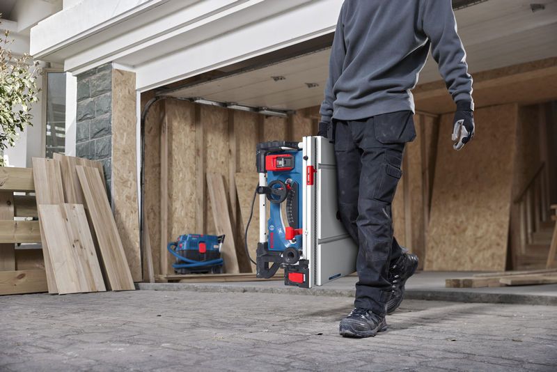 一名佩戴安全设备的人员在建筑工地携带便携式台锯。.