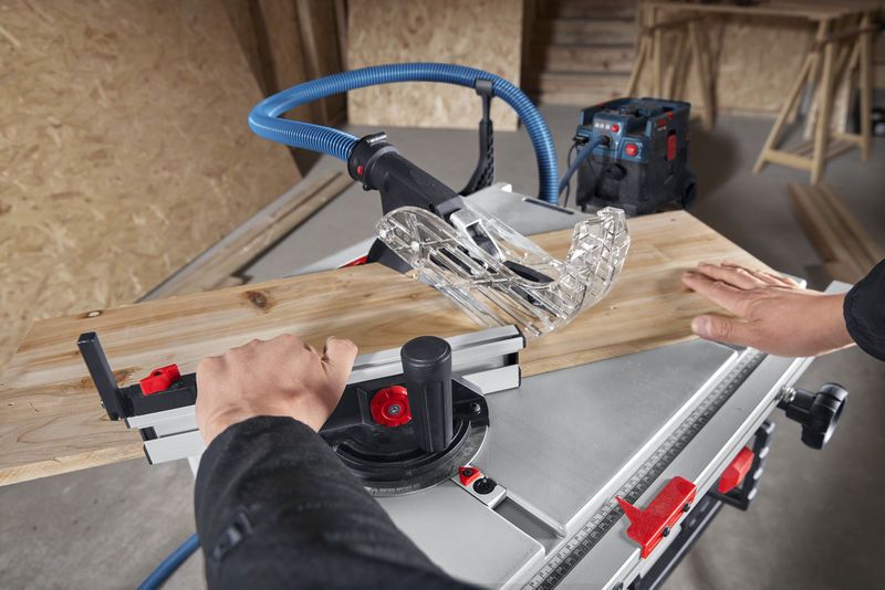 一名工人在车间用台锯引导木板。.