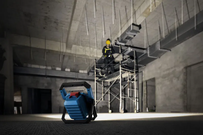 无绳工地灯照亮脚手架上佩戴安全设备的人员。.