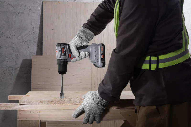 一名佩戴安全设备的人用无绳电钻钻木头。.