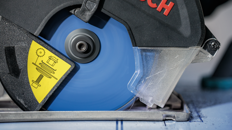 带有蓝色刀片的圆锯切割一块有标记的材料。.