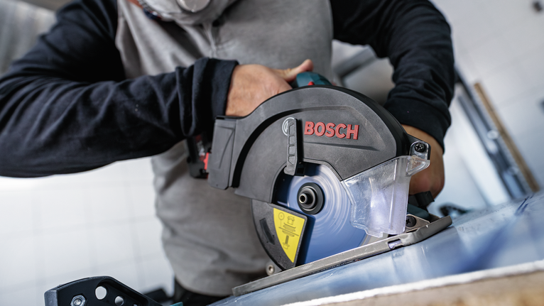 佩戴安全设备的人员用圆锯切割金属板。.