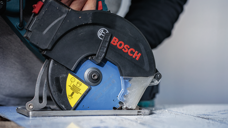 一名佩戴安全设备的人员使用圆锯切割一块材料。.