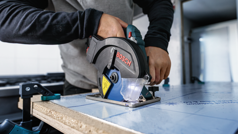 操作圆锯切割夹在工作台上的木板的人。.