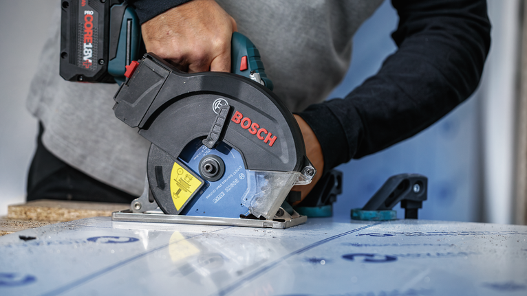 佩戴安全设备的人员使用圆锯切割层压板。.