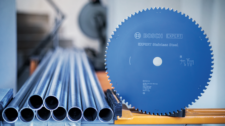 工业工作站上堆叠的金属管旁边的圆锯片。.