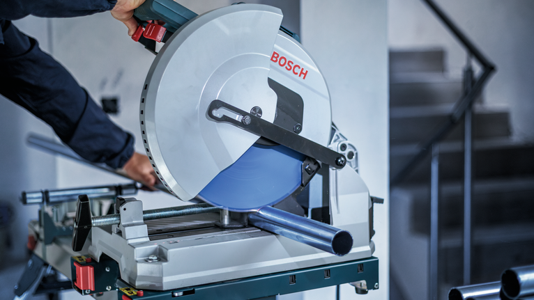 佩戴安全设备的人员用圆锯切割金属管。.