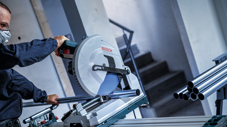 佩戴安全设备的人员用圆锯切割金属管道。.