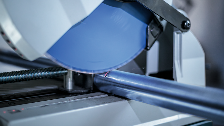 车间内，金属管道正被圆锯切割。.