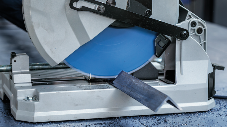 金属切断锯正在切割车间地板上的钢筋。.